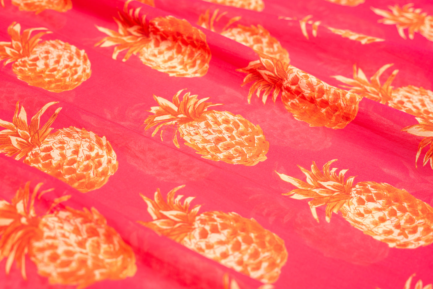 Close-up of orange pineapple print on pink cotton fabric