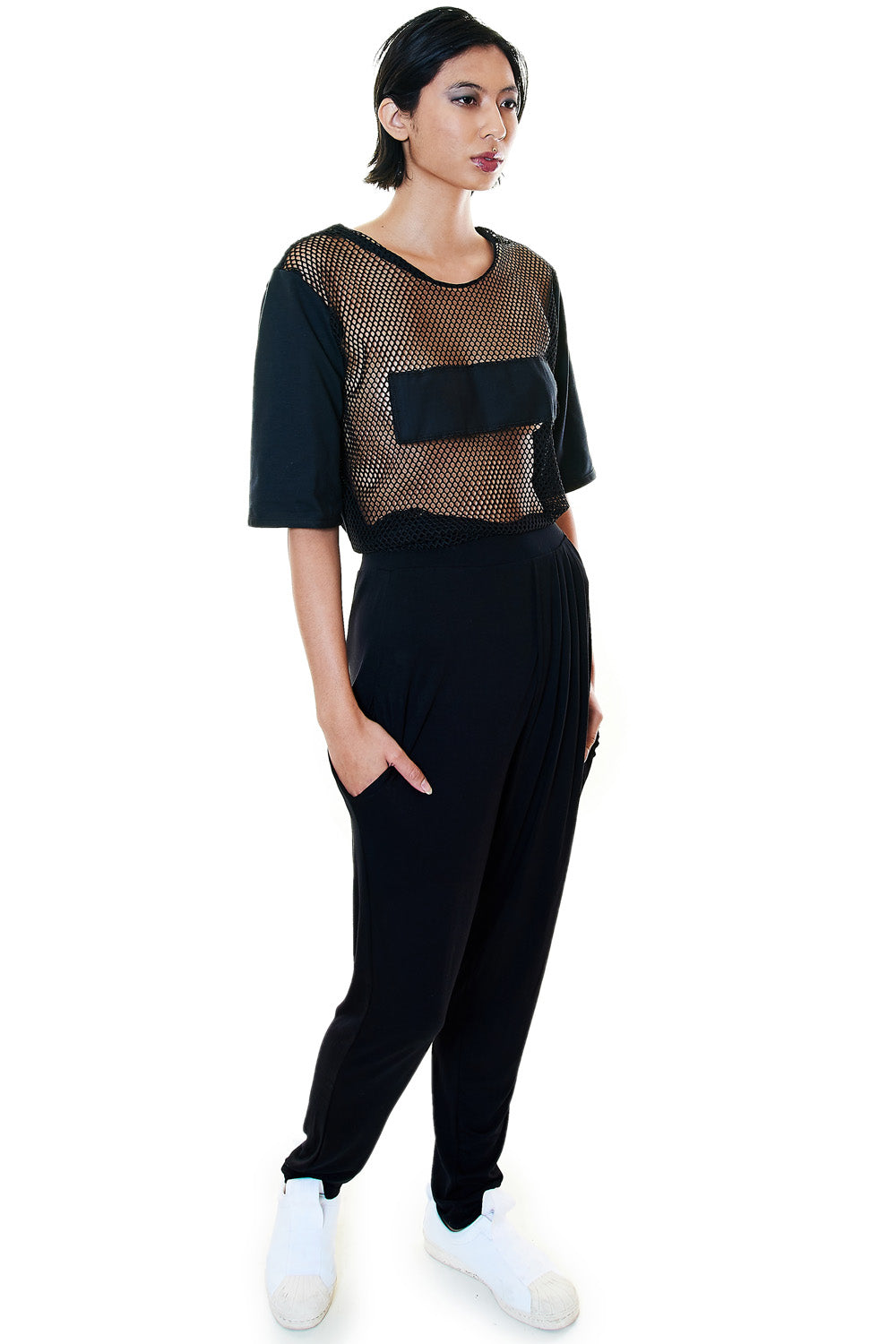 Model wearing a black mesh panel unisex tee with cotton sleeves and oversized front pocket – styled with black pants and white sneakers