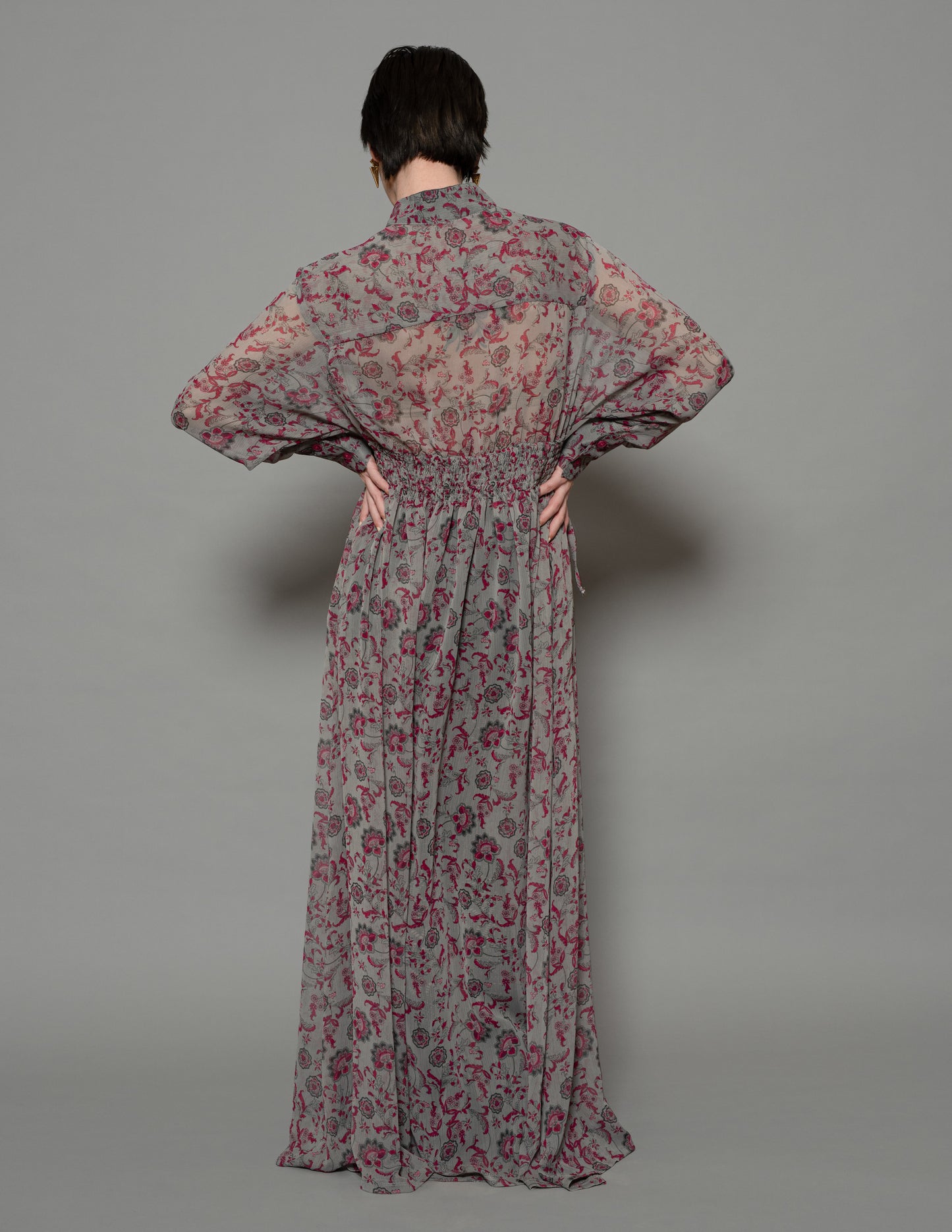 Back view of sheer floral chiffon dress with gathered waist and long flowing skirt.