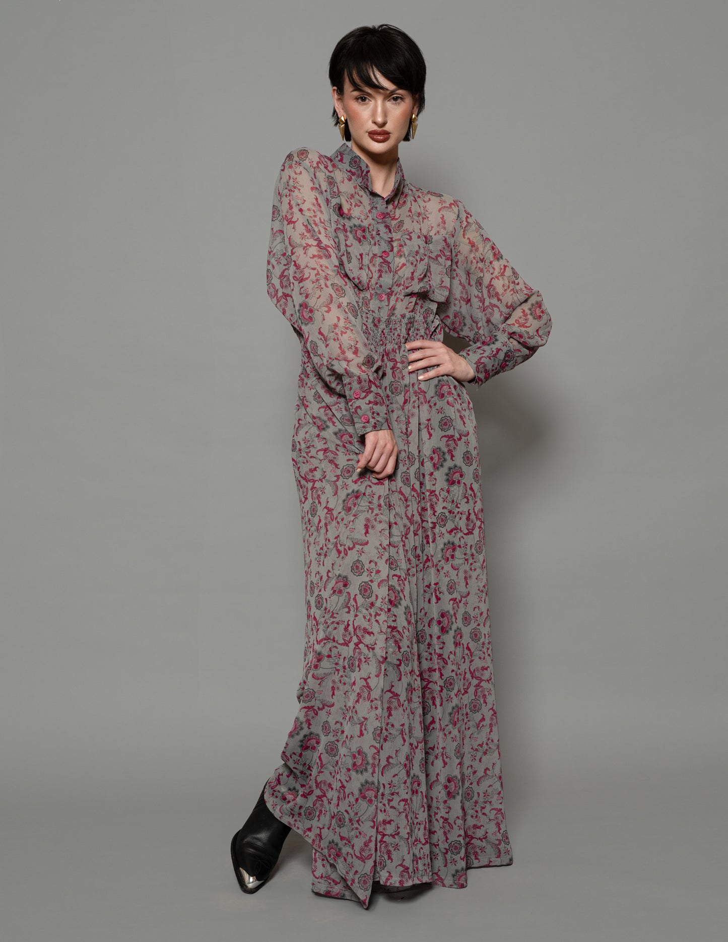 Model wearing gray floral maxi dress with red pattern, ruched waist, and bishop sleeves — front view.