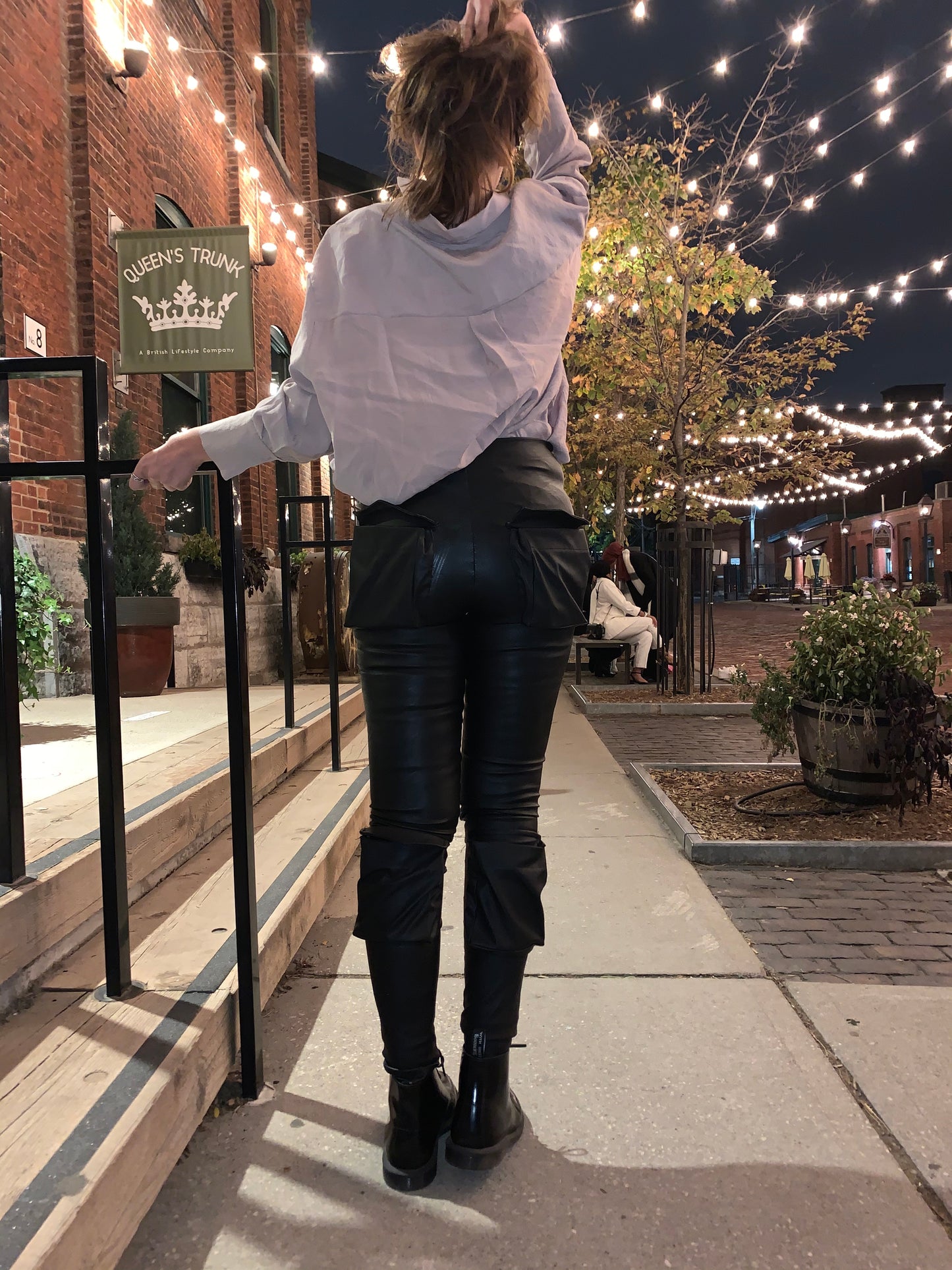 Woman wearing black leather leggings with utility pockets styled with ankle boots at night