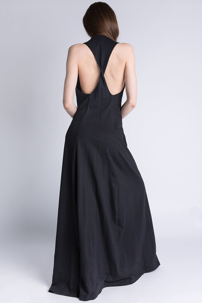 Woman wearing black jersey maxi dress with racerback design, photographed from the back."