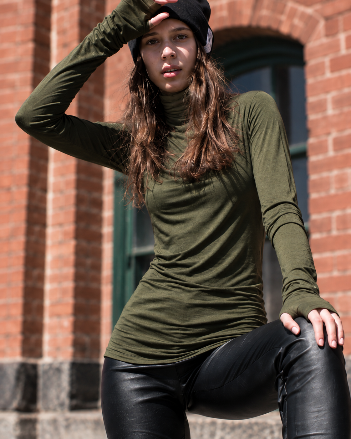 Woman wearing Casa Como olive green long sleeve turtleneck in an urban editorial setting