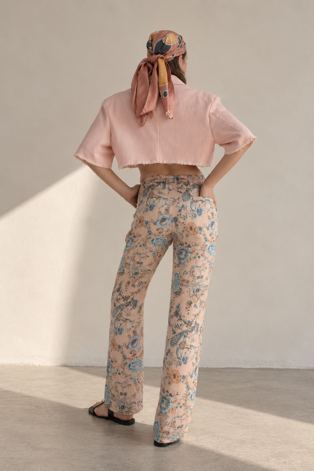 Back view of Casa Como floral relaxed trousers styled with a blush cropped blazer and patterned scarf.