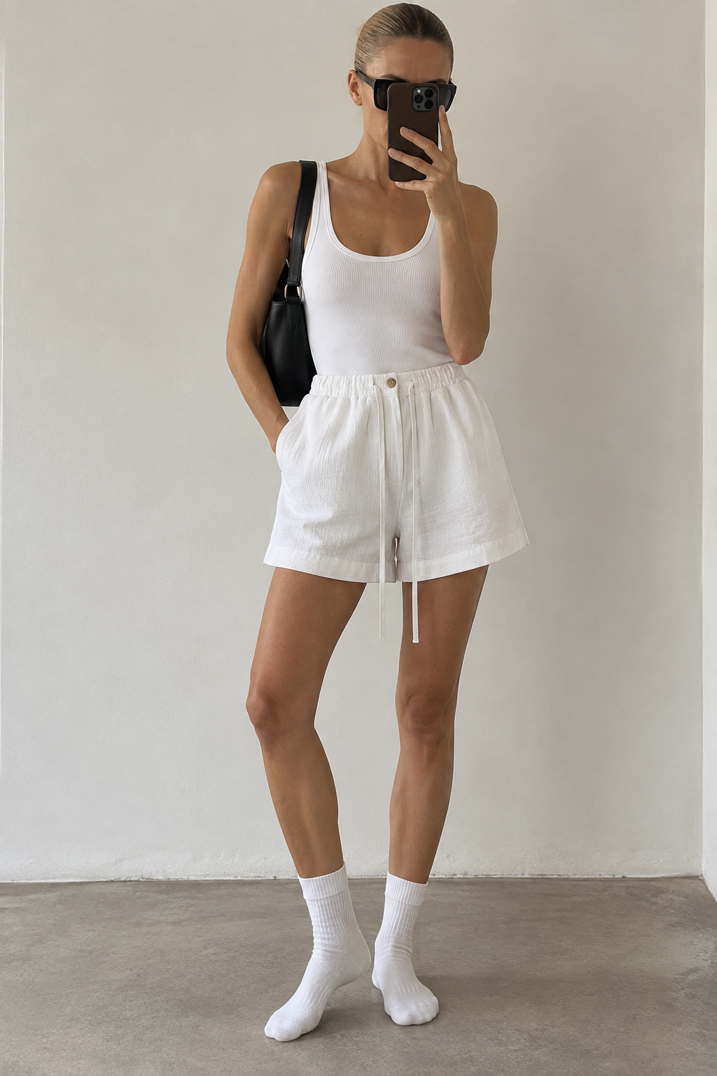 Model wearing Casa Como relaxed ivory shorts with a white tank in a minimalist tonal summer look.