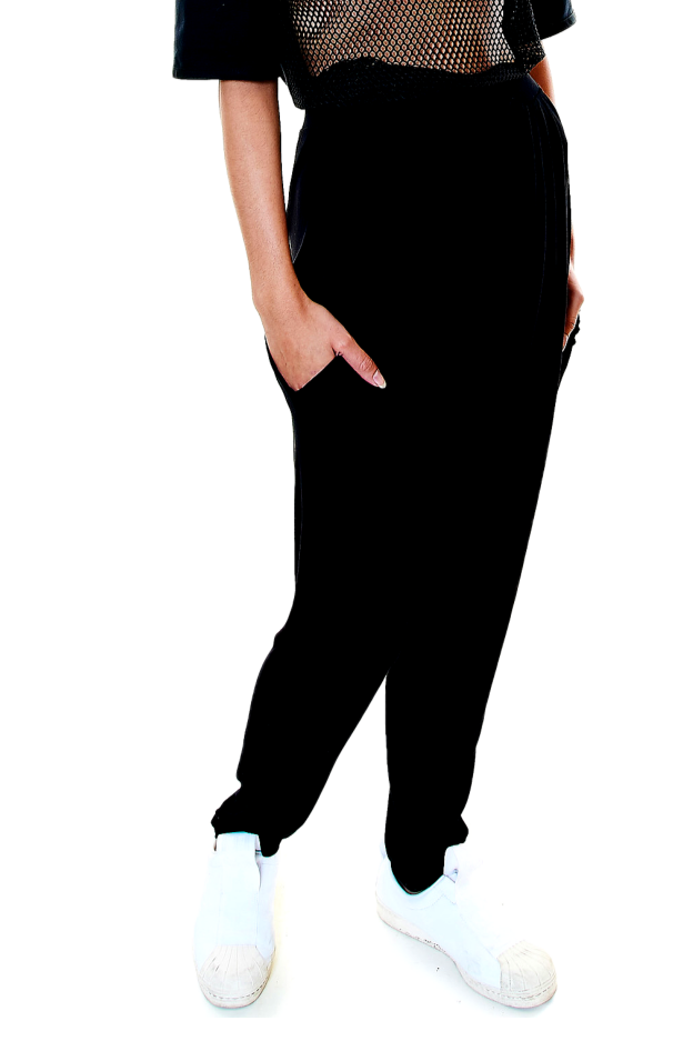Side view of pleated black pants styled with white sneakers